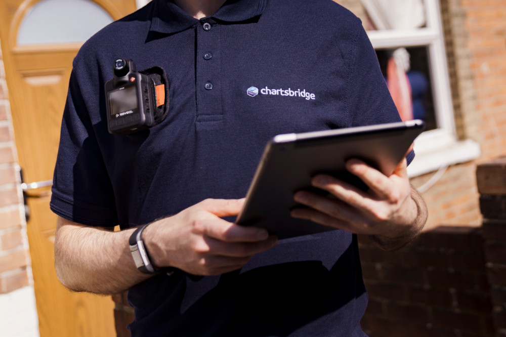 A Chartsbridge enforcement agent or bailiff carrying out a residential eviction wearing body-worn video and holding an iPad